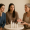 Three women of different ages discussing skincare products at a table.